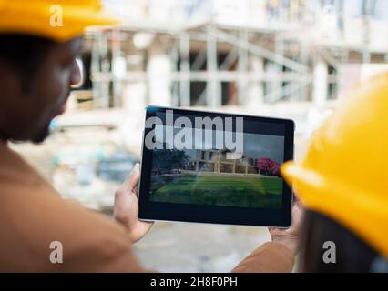 Ingenieure, die sich auf der Baustelle mit dem digitalen Rendering auf dem Tablet-PC anstellen Stockfoto