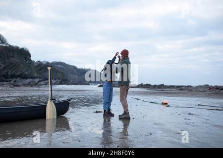 Pärchen bereitet sich auf Kanufahren am Strand vor Stockfoto