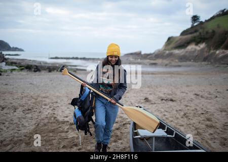 Junge Frau mit Rudern beim Kanu am Winterstrand Stockfoto