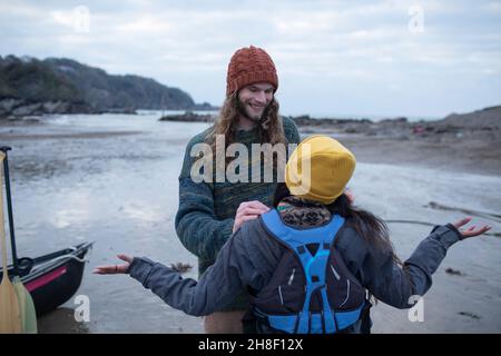 Glückliches junges Paar, das sich auf Kanufahren am Strand vorbereitet Stockfoto