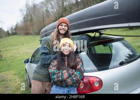 Portrait glückliches junges Paar außerhalb Auto mit Kanu auf der Oberseite Stockfoto