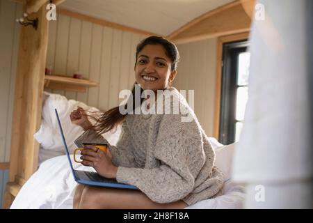Portrait glückliche junge Frau mit Laptop im Bett Stockfoto
