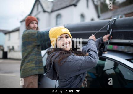 Portrait glücklich junges Paar Befestigung Kanu auf der Oberseite des Autos Stockfoto