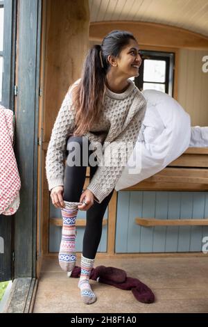 Junge Frau, die in einer winzigen Hütte Socken anlegt Stockfoto