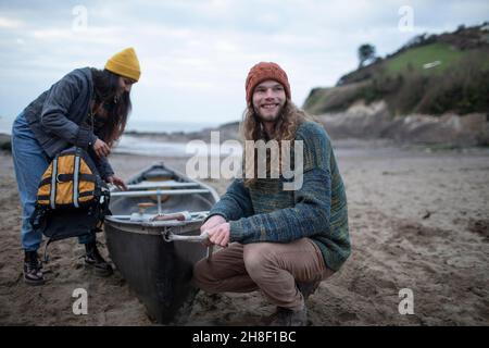 Lächelndes junges Paar mit Kanu am Strand Stockfoto