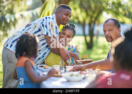Mutter und Sohn umarmten und feierten Geburtstag am Terrassentisch Stockfoto