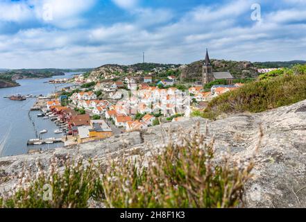 Fjällbacka, Schweden - 9. Juni 2021: Blick vom Hügel auf die kleine schwedische Stadt mit ihren bunten Gebäuden und der alten Kirche Stockfoto