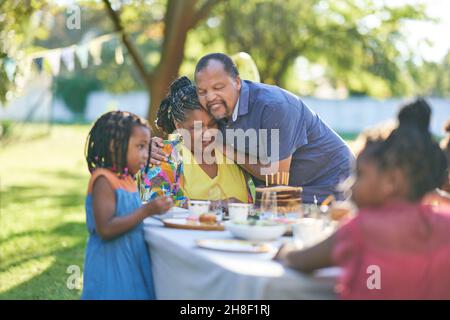Glückliches Paar, das Geburtstag mit der Familie am Sommerterrasse-Tisch feiert Stockfoto