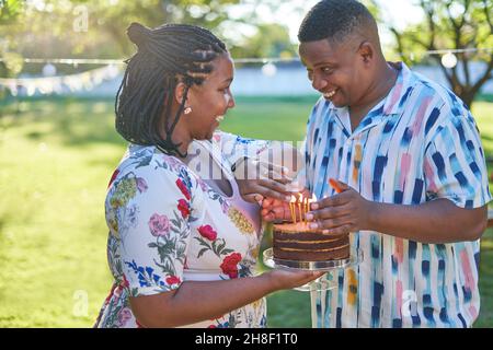 Glückliches Paar feiert Geburtstag mit Kuchen und Kerzen im Park Stockfoto