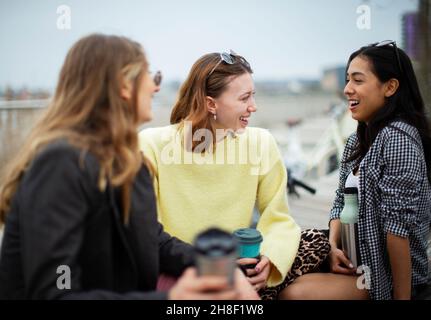 Glückliche junge Freundinnen reden und trinken Kaffee Stockfoto