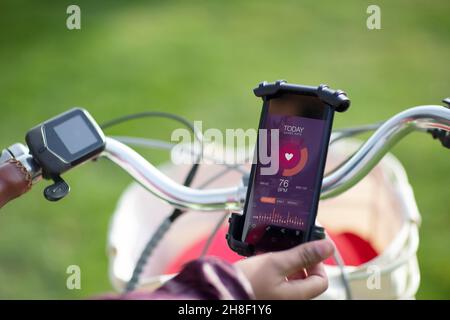 POV Frau auf dem Fahrrad Überprüfung der Herzfrequenz mit Smartphone-App Stockfoto