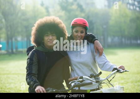 Portrait glücklich teen paar Umarmung auf Fahrrädern im Park Stockfoto