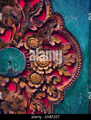 Vertikale Nahaufnahme der roten, blumengemusterten Holzplatte auf dem blauen Hintergrund Stockfoto