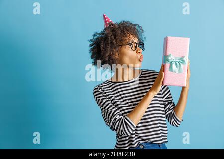 Staunende afrikanische Frau im Geburtstagshut mit Geschenk Stockfoto