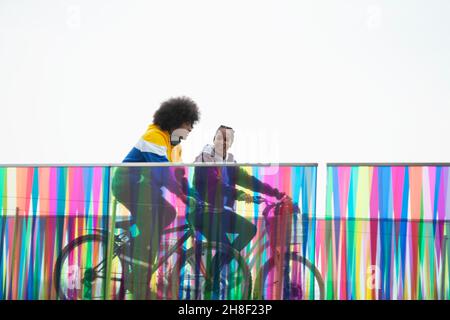 Teenager-Freunde, die auf einem modernen Steg Fahrrad fahren Stockfoto