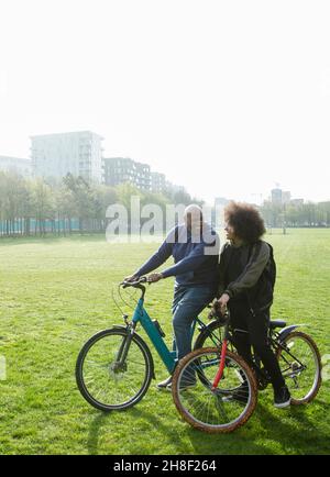 Vater und Sohn reiten Fahrräder im sonnigen Stadtpark Stockfoto