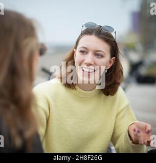 Glückliche junge Frau im Gespräch mit einem Freund Stockfoto