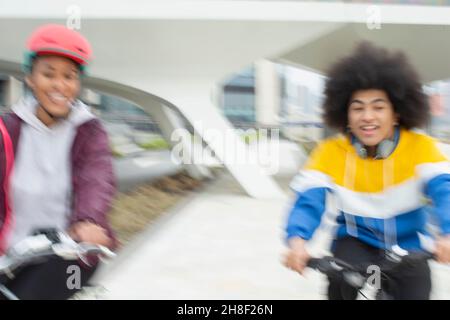 Glückliche Teenager-Freunde, die in der Stadt Fahrräder reiten Stockfoto
