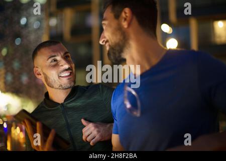 Glückliche Männer, männliche Freunde, die nachts reden Stockfoto