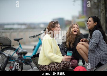 Glückliche junge Freundinnen, die in der Stadt lachen Stockfoto