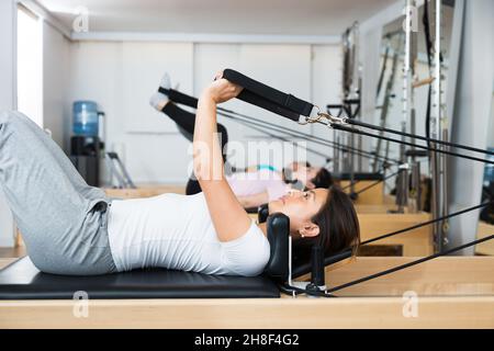 Frauen, die Pilates-Übungen auf Pilates-Maschinen liegen Stockfoto