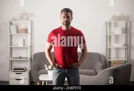 Kerl in roten T-Shirt halten die Hände in der Tasche, Mode Stockfoto