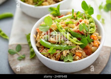 Frühstück gebratener Reis mit grünen Erbsen und Karotten und frischen Erbsensprossen in Schüsseln Stockfoto