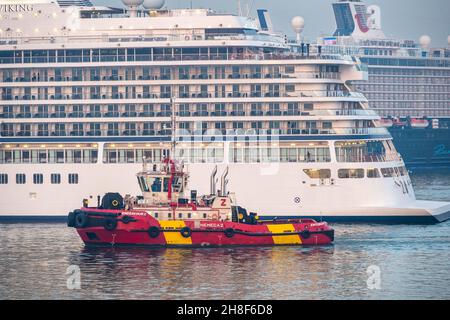 Rot-gelbes Schlepper neben einem großen Kreuzschiff Stockfoto