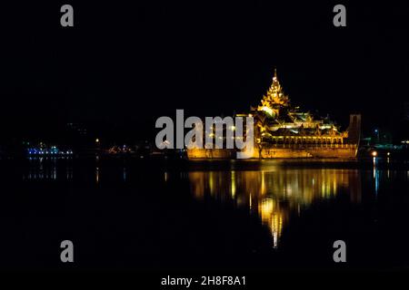 YANGON, MYANMAR (BURMA) - 19. Aug 2017: Karaweik Palace Hall Barge, beleuchtet golden hell in der Nacht reflektieren auf Kandawgyi See, Yangon, Myanmar, Burma Stockfoto