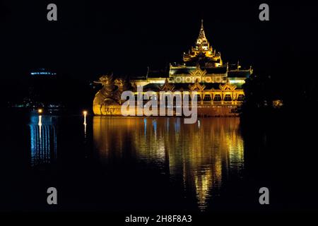 YANGON, MYANMAR (BURMA) - 19. Aug 2017: Karaweik Palace Hall Barge, beleuchtet golden hell in der Nacht reflektieren auf Kandawgyi See, Yangon, Myanmar, Burma Stockfoto