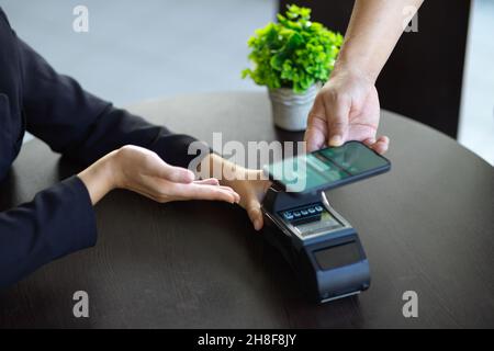 Zugeschnittenes Bild einer Frau, die ihre Waren per Online-Zahlung mit Zahlungsterminal-Maschine bezahlt. Mobile Banking-Anwendung. Stockfoto