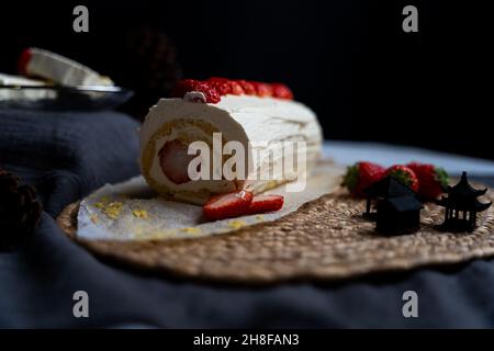 Erdbeerrollkuchen und chinesische Dekoration mit schwarzem Hintergrund Stockfoto