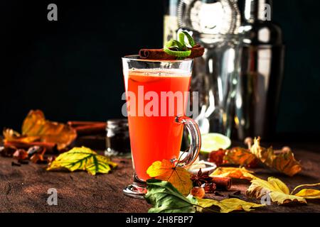 Heißer gebutterter Rum, winterlicher Cocktail mit Apfelsaft, dunklem Rum, Honig, Zimt im Glas auf Holzgrund Stockfoto