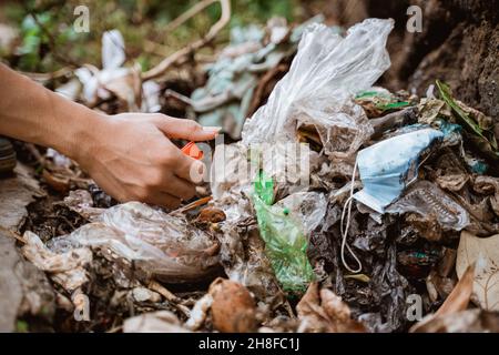 Plastikmüll von Hand aufnehmen und in den Abfallbeutel geben Stockfoto