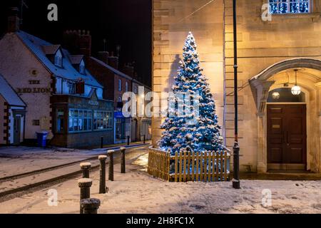 Weihnachtsbaum und Lichter vor dem rathaus von brackley im Abendschnee. Brackley, Northamptonshire, England Stockfoto