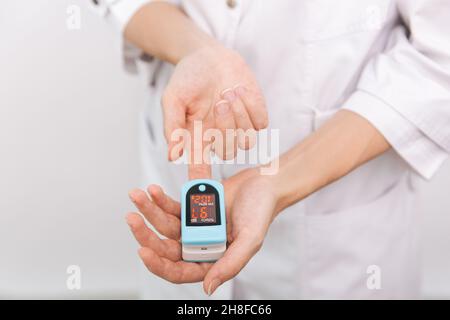 Pulsoximeter mit der Hand des Arztes auf Weiß isoliert. Das Konzept eines tragbaren digitalen Geräts zur Messung der Sauerstoffsättigung von Personen. Messung von Sauerstoff Stockfoto