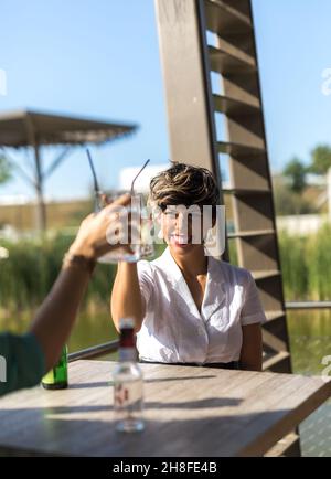 Zwei Freunde toasten mit ihren Getränken auf einer Außenterrasse Stockfoto