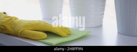 Hand in gelben Handschuh wischt Wahrheit mit Lappen auf Fensterbank Stockfoto