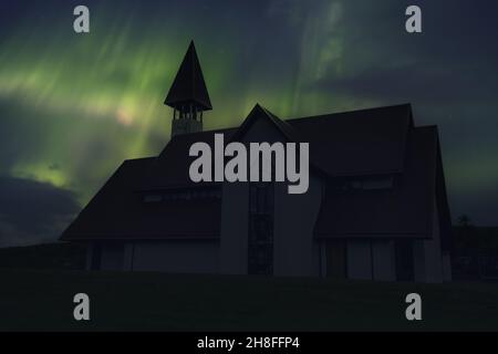 Schöne traditionelle Kirche in der Nähe von Reykjavik Stadt bei einer Nacht mit schönen Nordlichtern. Island Stockfoto