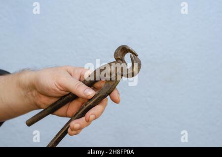 Ein Mann hält alte Zangen in der Hand. Ein rostetes Metallhandwerkzeug. Nahaufnahme. Selektiver Fokus. Stockfoto