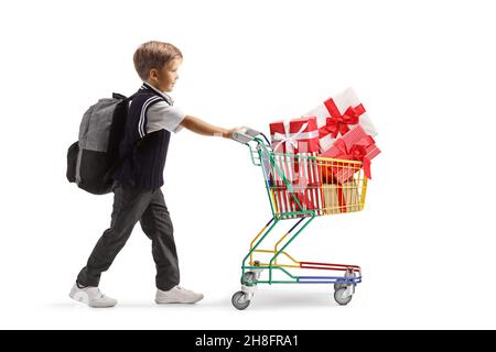 In voller Länge Profilaufnahme eines Schuljungen, der einen Mini-Einkaufswagen voller verpackter Geschenke auf weißem Hintergrund schiebt Stockfoto