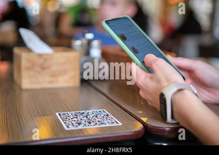 Nahaufnahme der Gäste, die eine Mahlzeit im Restaurant bestellen, während der QR-Code mit dem Mobiltelefon gescannt wird, um ein Online-Menü zu erhalten. Stockfoto