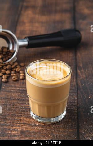 Cortado-Kaffee mit Kaffeebohnen daneben. Traditioneller Kaffee in Spanien. Stockfoto