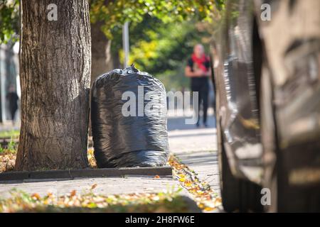 Stapel schwarzer Müllsäcke voller Müll, die auf der Straßenseite zur Abholung liegen. Abfallentsorgungskonzept. Stockfoto