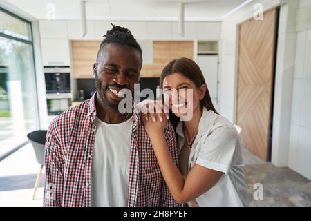 Lächelnde Dame, die sich auf die Schulter eines fröhlichen Mannes lehnt Stockfoto