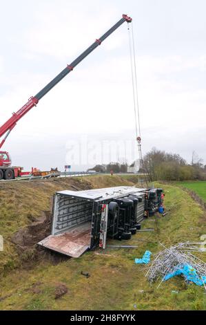 Padenstedt, Deutschland. 30th. November 2021. Der am Unfall beteiligte Lkw liegt im Graben neben der Zufahrtsstraße. Ein mit 22 Tonnen Schweinehälften beladener LKW hat auf der Zufahrtsstraße von der B 205 zur B 7 bei Neumünster-Süd eine Leitplanke durchbrochen, wodurch die Zufahrtsstraße stundenlang gesperrt wurde. Quelle: Jonas Walzberg/dpa/Alamy Live News Stockfoto