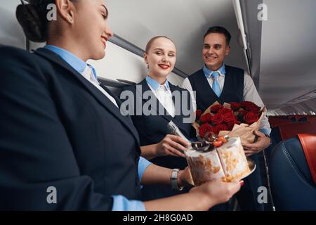 Zwei weibliche und männliche Flugbegleiter, die lächelnd Geschenke halten Stockfoto