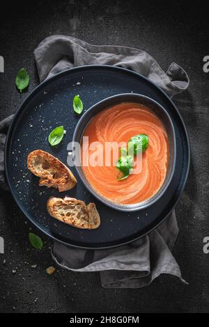 Hausgemachte Tomatensuppe mit Basilikum und Toast. Rote Tomatensuppe in blauer Keramik. Stockfoto