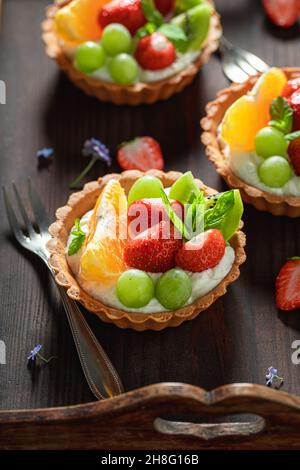 Köstliche Mini-Tarte mit verschiedenen Früchten. Einfaches Fruchtdessert. Tarte mit Creme und Früchten. Stockfoto