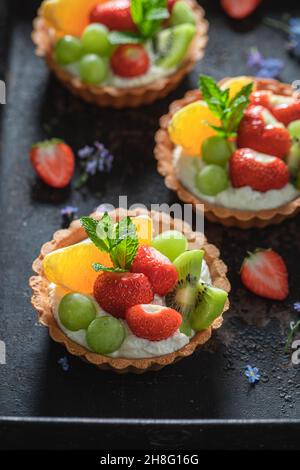 Köstliche Mini-Tarte mit verschiedenen Früchten. Süßes Sommerdessert. Tarte mit Creme und Früchten. Stockfoto